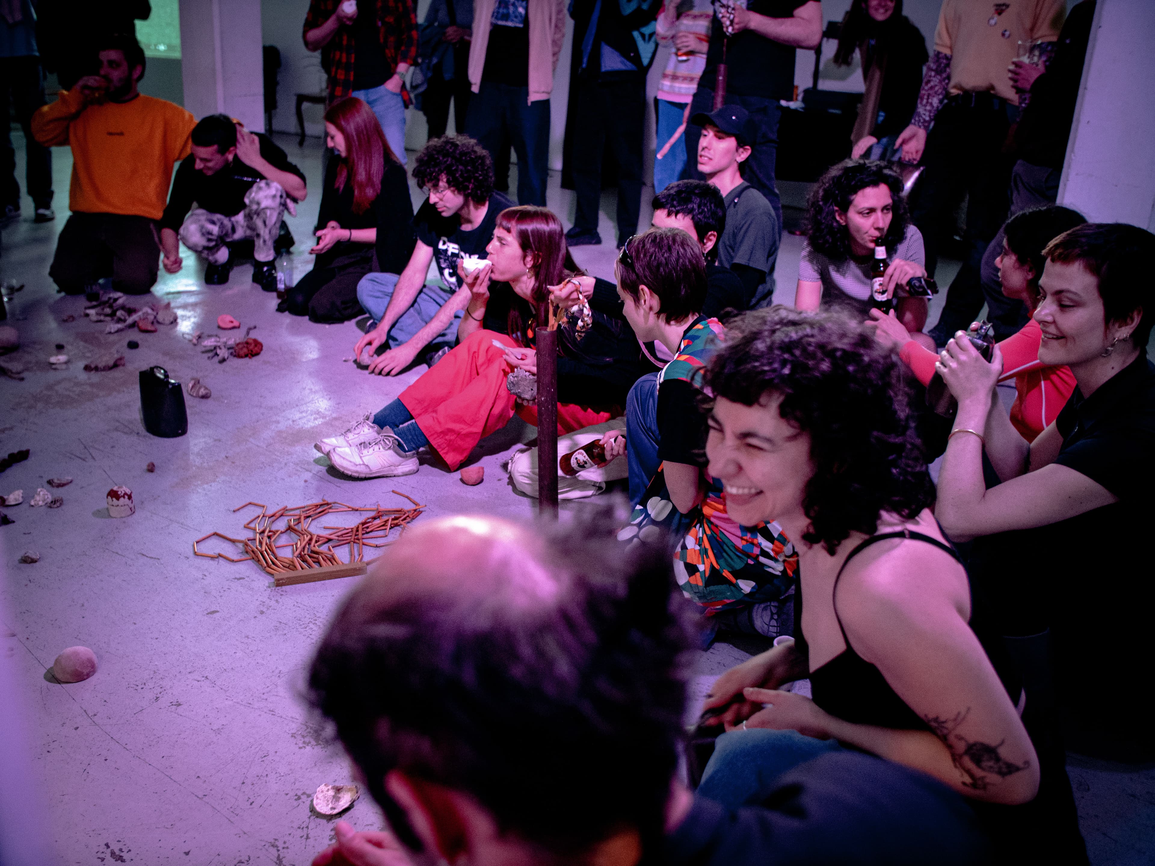 A group of young people sitting on the floor plays with instruments such as ceramics whistles, metal bells, rattles - some smile and laugh - there is a joyful atmosphere