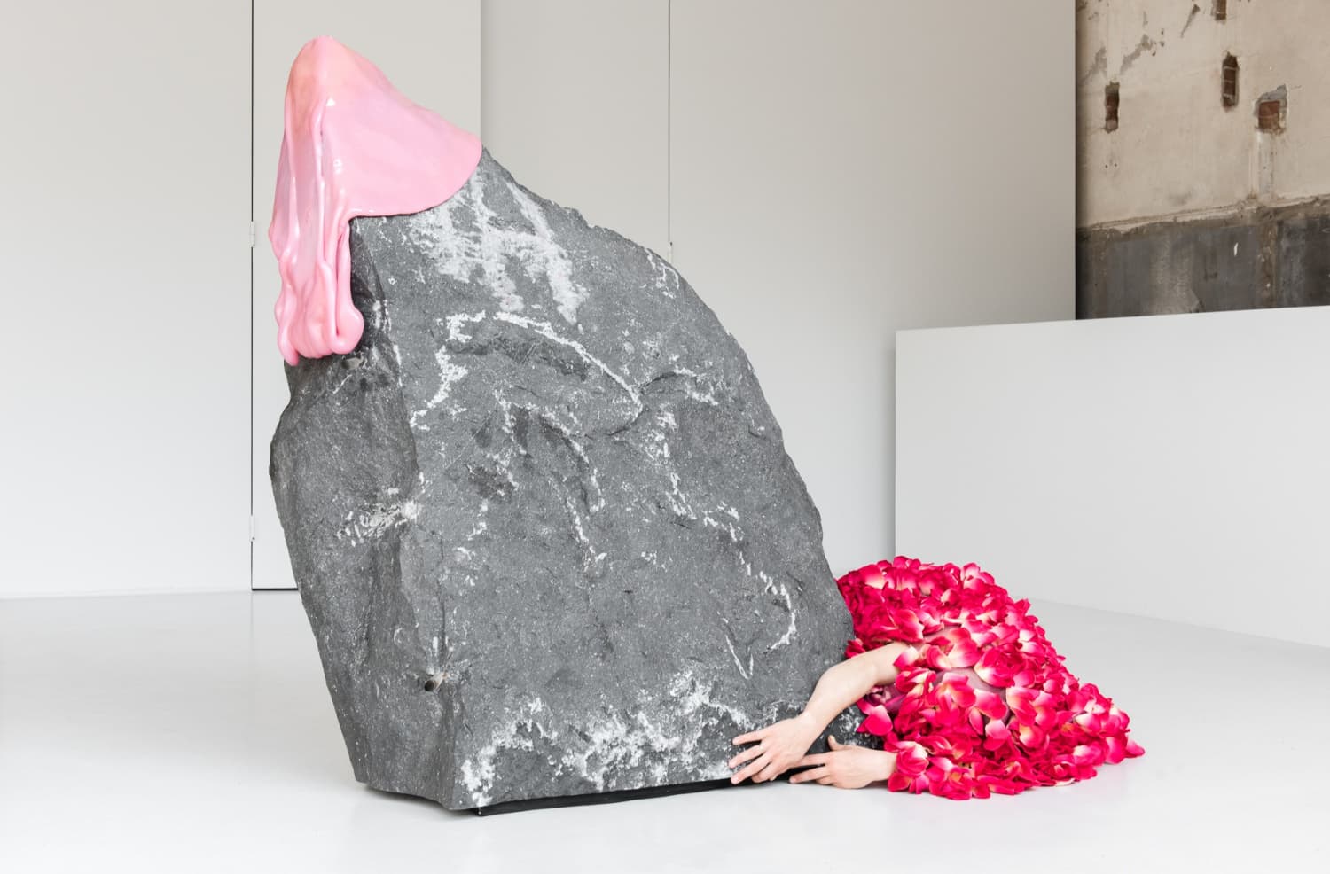 The image shows a rock shaped sculpture and a body curled around it at the base.