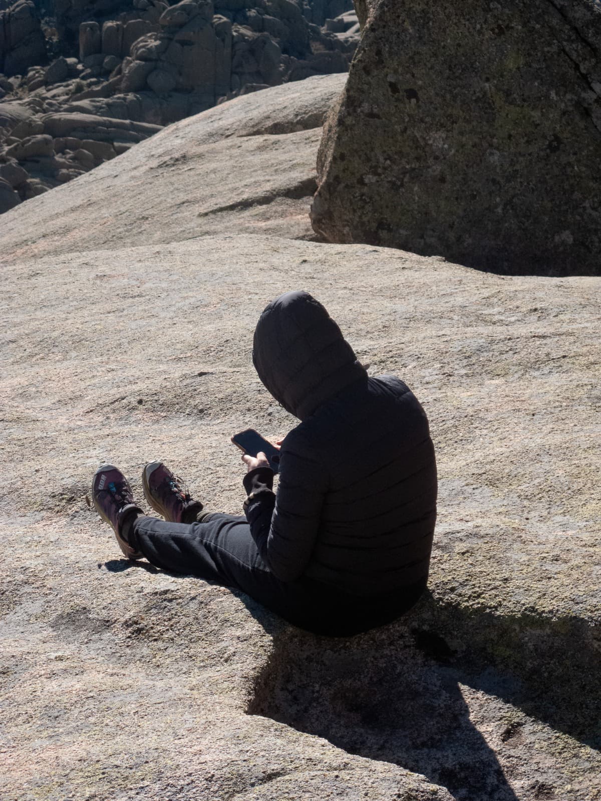 Image of the artist standing on top of a mountain while scrolling on her phone.