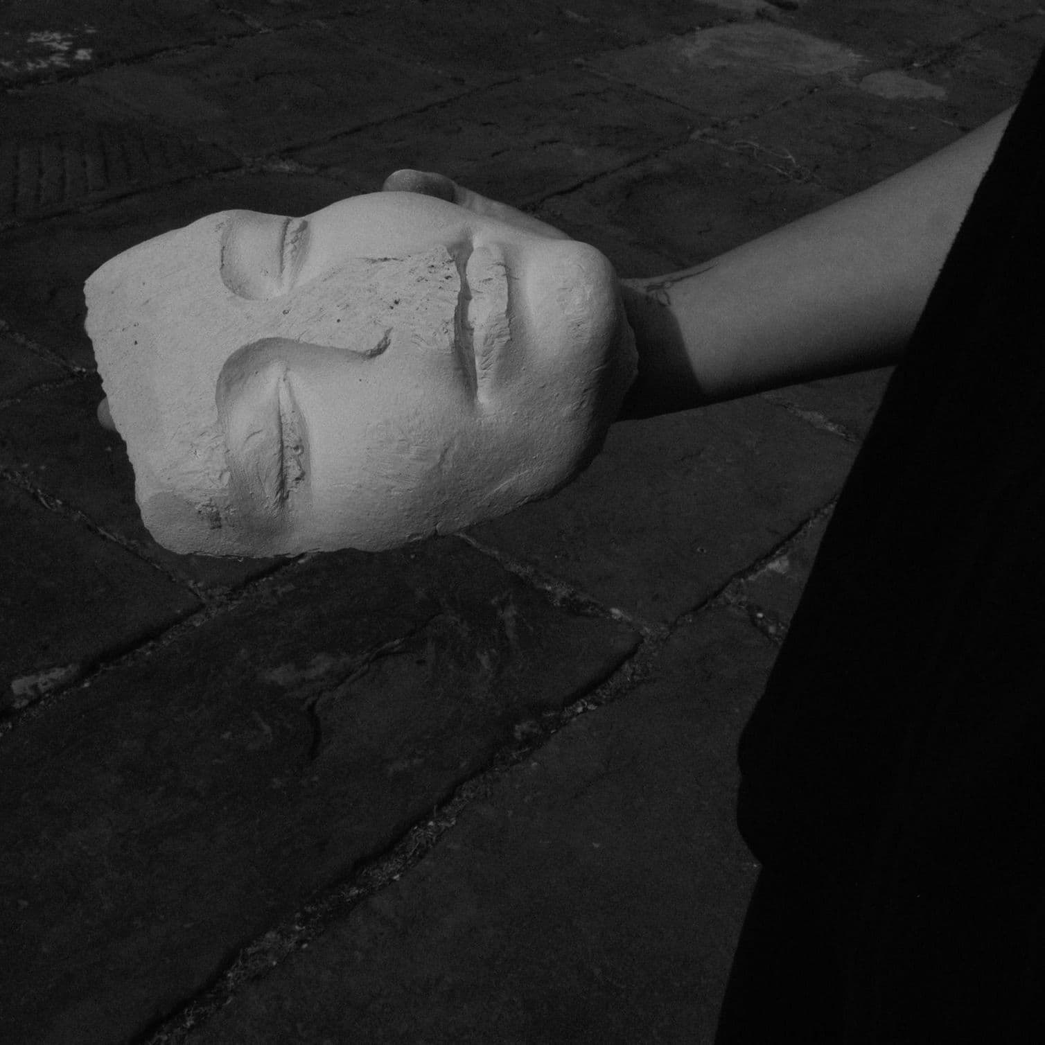 Hand holding a face mask made out of plaster worn down around its forehead and nose from friction 