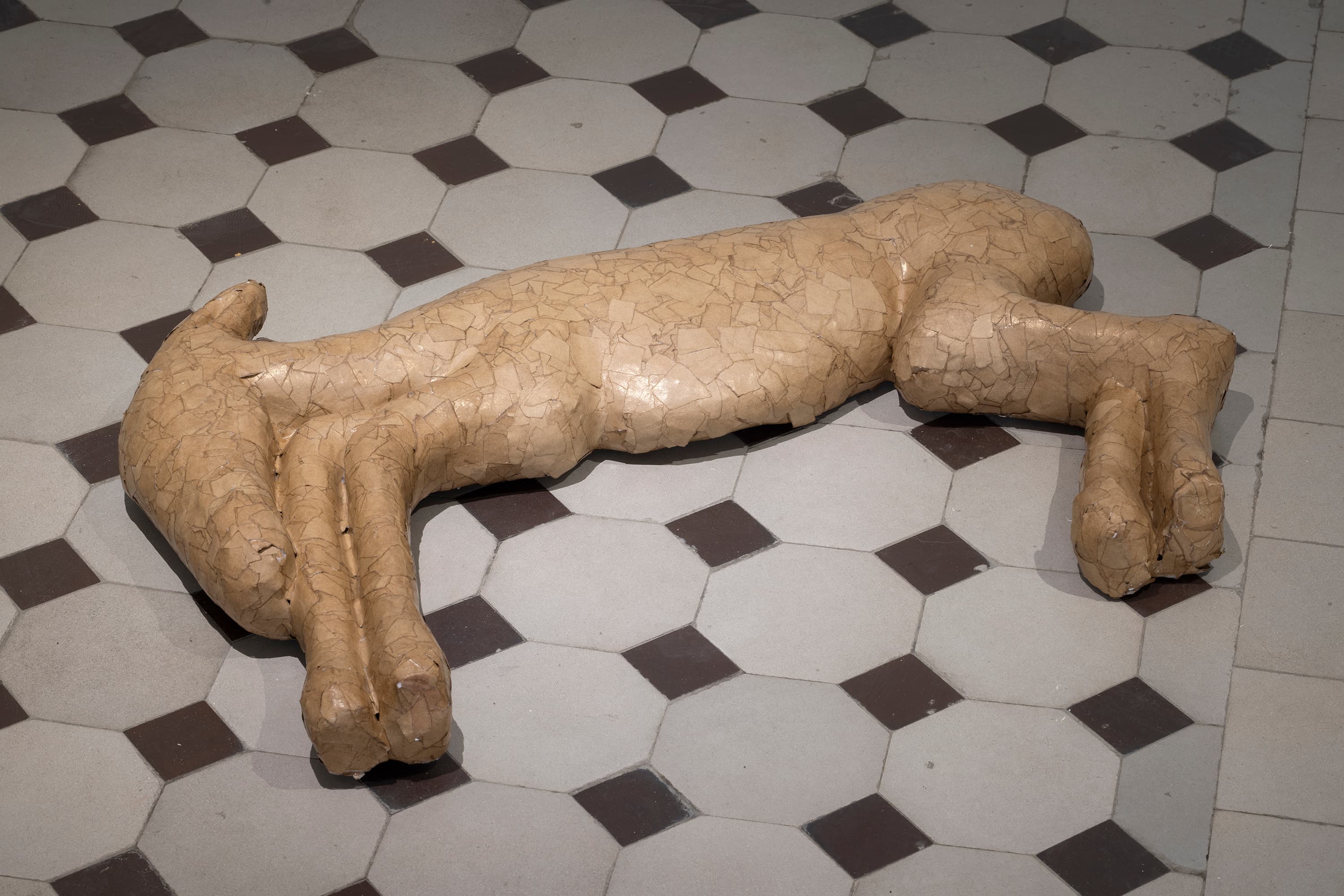 a papier-mache sculpture of a small horse calf like animal lies on the floor.